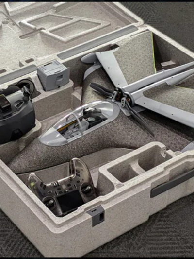 Quadcopter with propellers in a foam transport case, along with FPV goggles and a remote controller.
