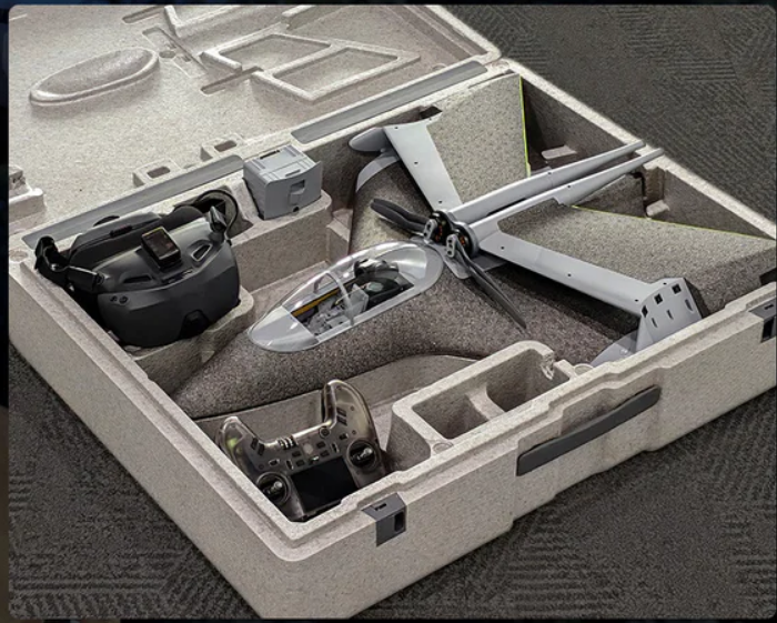 Quadcopter with propellers in a foam transport case, along with FPV goggles and a remote controller.